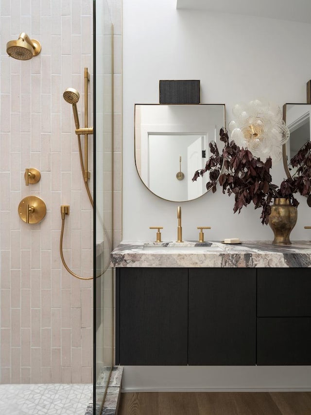 bathroom featuring tiled shower, vanity, and wood-type flooring