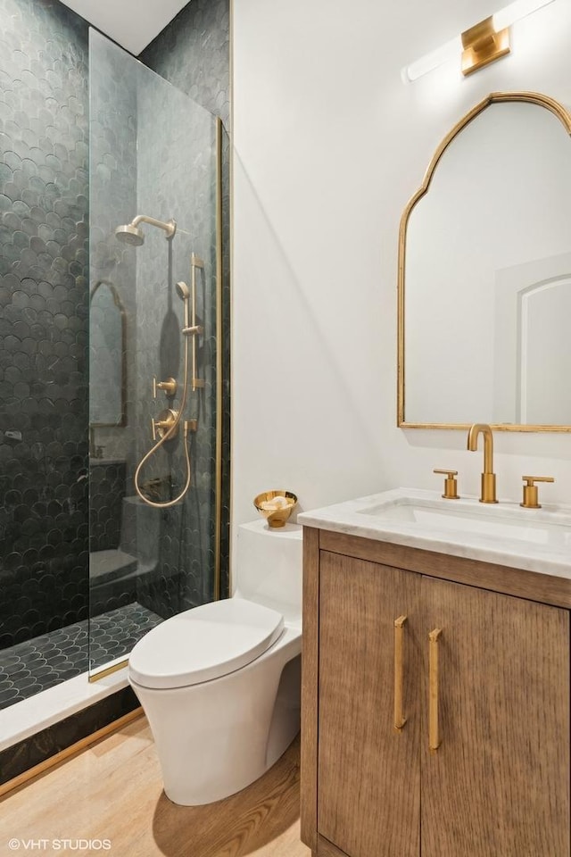 bathroom with vanity, toilet, and a tile shower