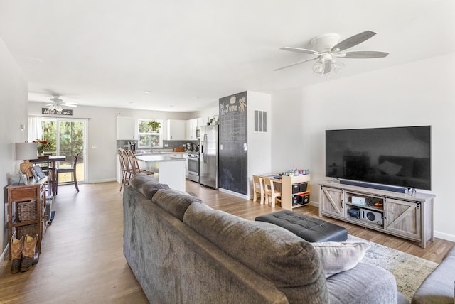 living room with ceiling fan, sink, and light wood-type flooring