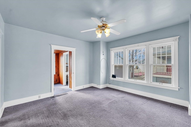 spare room featuring dark carpet and ceiling fan