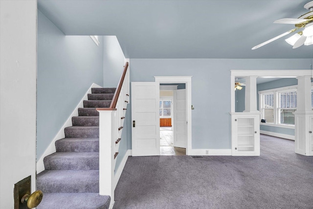 stairs featuring decorative columns, carpet, and ceiling fan