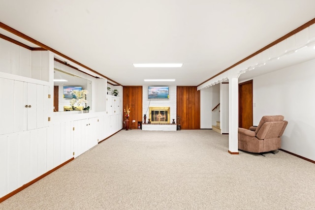 basement with a fireplace, ornamental molding, wooden walls, and carpet floors