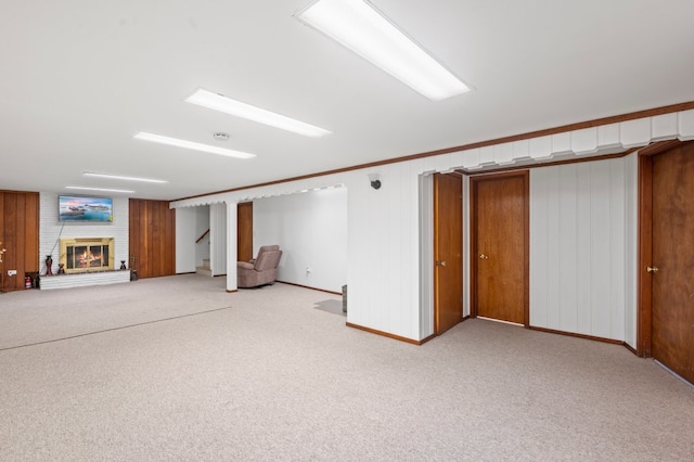 basement with light colored carpet, wood walls, and a fireplace