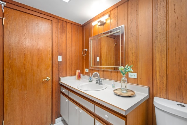 bathroom with vanity, toilet, and wood walls