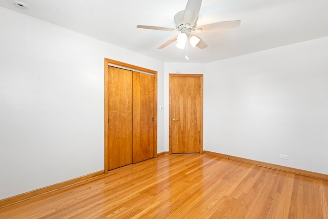 unfurnished bedroom featuring ceiling fan, a closet, and light wood-type flooring