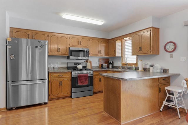 kitchen featuring sink, light hardwood / wood-style flooring, kitchen peninsula, and appliances with stainless steel finishes