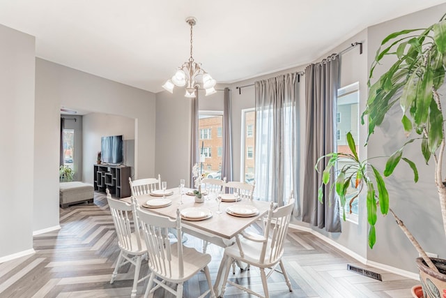 dining room with light parquet flooring and a notable chandelier