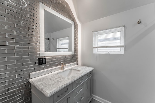 bathroom featuring vaulted ceiling, decorative backsplash, and vanity