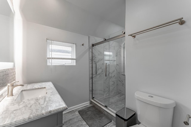 bathroom with a shower with shower door, toilet, and vanity