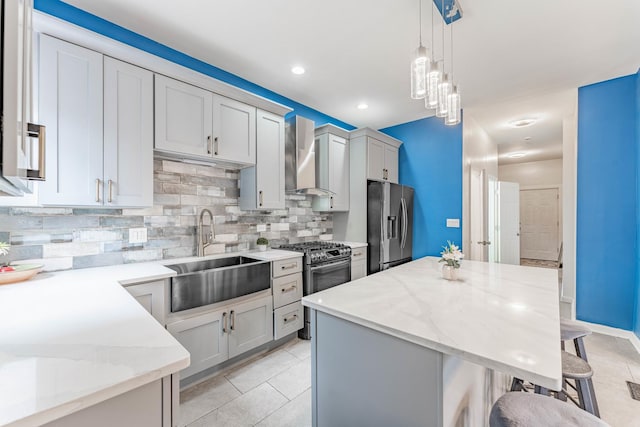 kitchen with stainless steel appliances, sink, light stone countertops, a breakfast bar, and wall chimney range hood