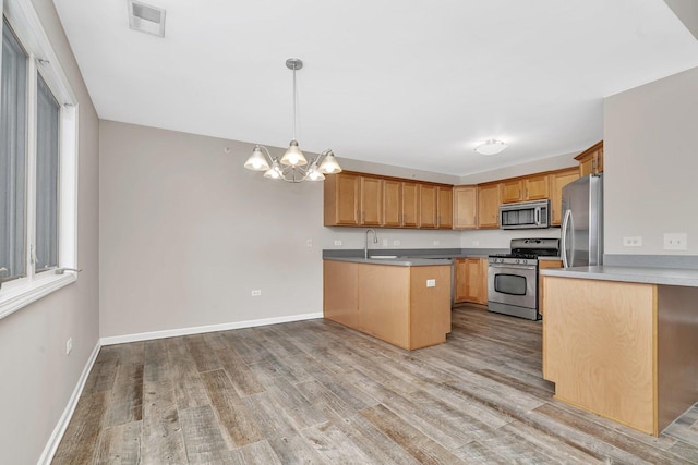 kitchen featuring kitchen peninsula, an inviting chandelier, light hardwood / wood-style flooring, hanging light fixtures, and stainless steel appliances