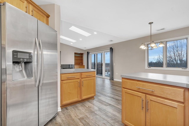 kitchen featuring light hardwood / wood-style floors, stainless steel refrigerator with ice dispenser, a notable chandelier, lofted ceiling with skylight, and hanging light fixtures