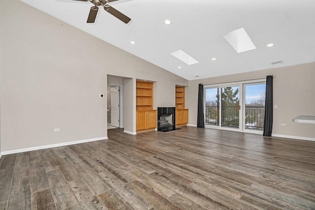 unfurnished living room with ceiling fan, dark wood-type flooring, high vaulted ceiling, and a skylight