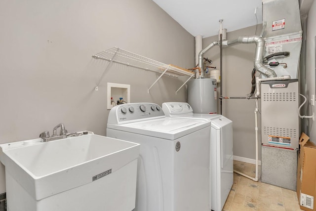 laundry area with water heater, washer and clothes dryer, and sink