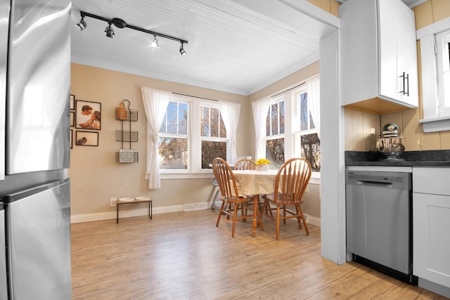 dining area with ornamental molding and light hardwood / wood-style floors