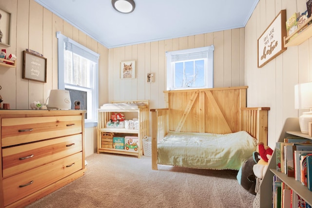 carpeted bedroom with wooden walls, multiple windows, and ornamental molding