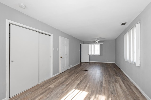 unfurnished bedroom featuring hardwood / wood-style flooring, a closet, and ceiling fan