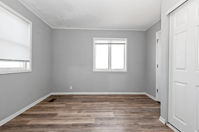 empty room with ornamental molding, a wealth of natural light, and dark hardwood / wood-style flooring