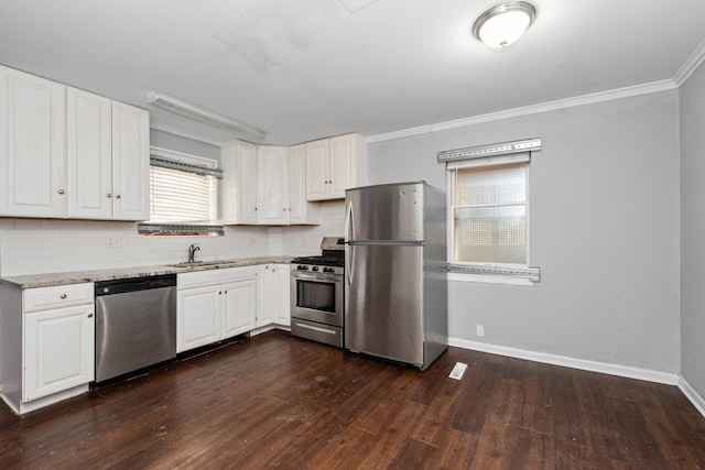 kitchen with light stone countertops, appliances with stainless steel finishes, ornamental molding, and white cabinets