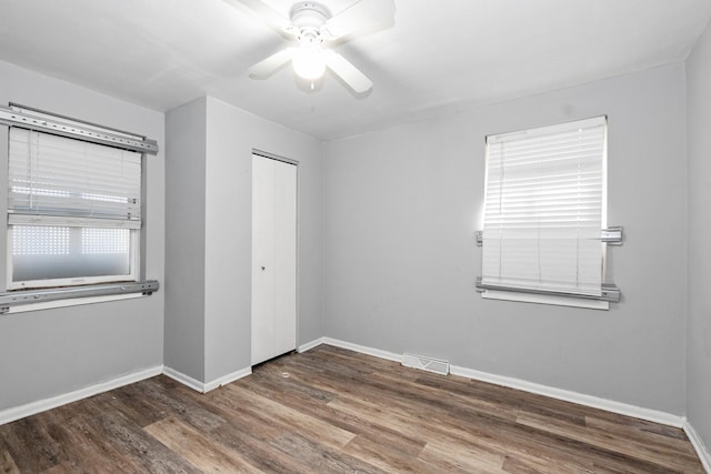 unfurnished bedroom with dark wood-type flooring, a closet, and ceiling fan