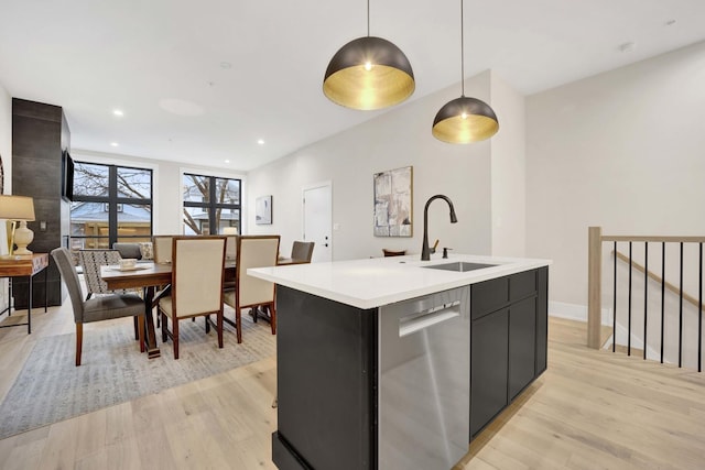 kitchen featuring dishwasher, light countertops, light wood finished floors, and a sink