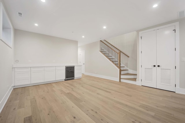 interior space with visible vents, light wood-style flooring, beverage cooler, recessed lighting, and stairs