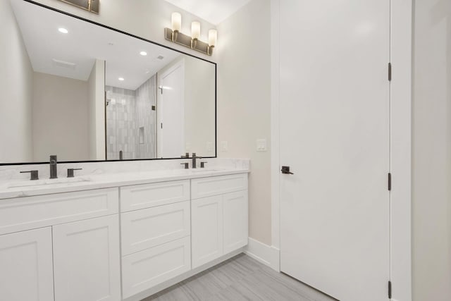 bathroom with a shower stall, recessed lighting, double vanity, and a sink