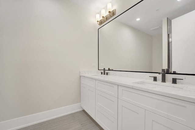 bathroom with a sink, baseboards, recessed lighting, and double vanity