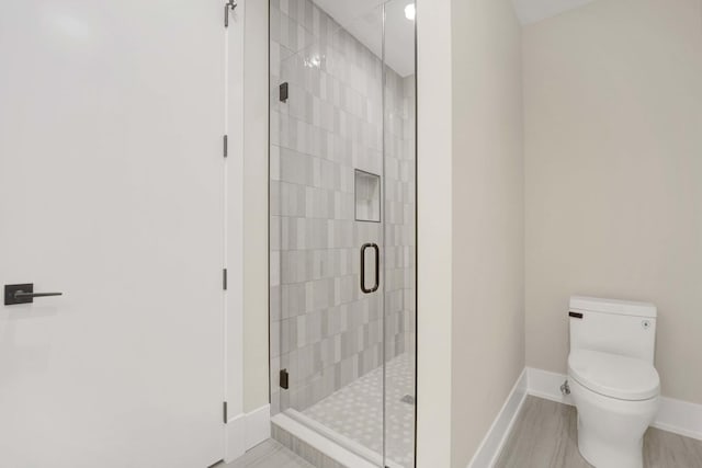 full bathroom featuring a shower stall, toilet, and baseboards