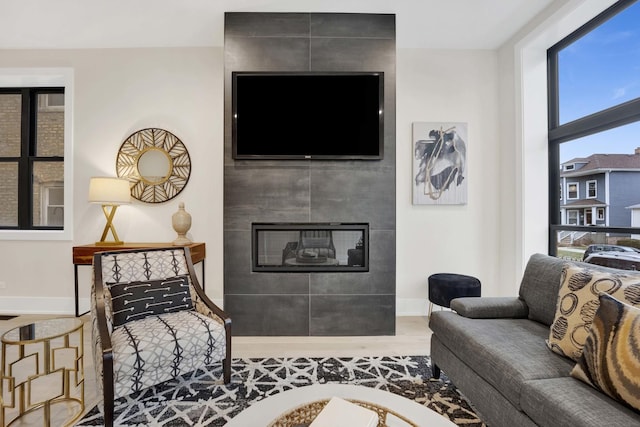 living room with wood finished floors, baseboards, and a tile fireplace