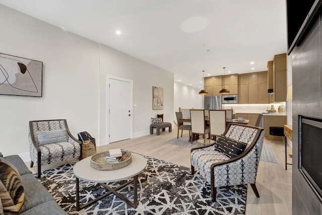 living area featuring recessed lighting, baseboards, and light wood finished floors