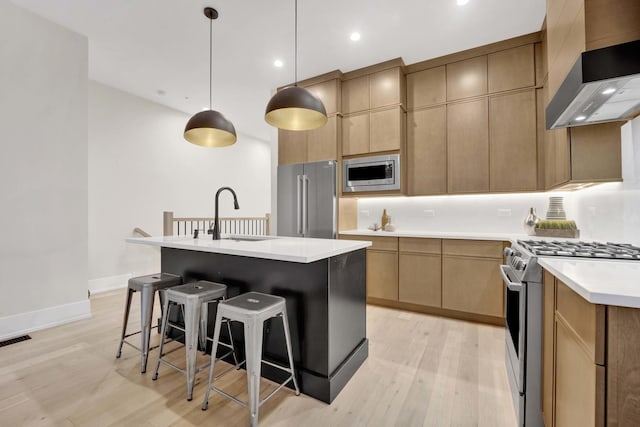 kitchen with visible vents, a breakfast bar area, appliances with stainless steel finishes, wall chimney exhaust hood, and a sink