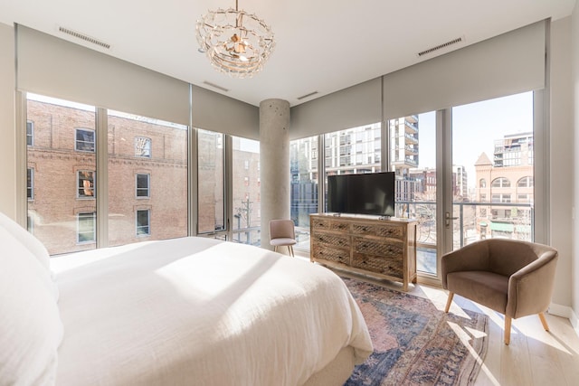 bedroom featuring expansive windows, access to exterior, hardwood / wood-style floors, and a notable chandelier