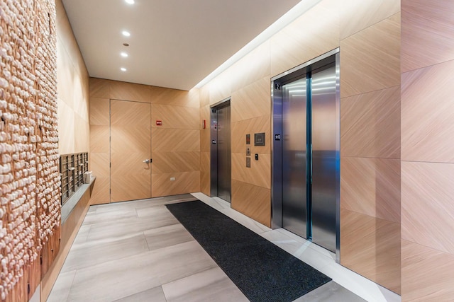 hallway featuring mail boxes, elevator, tile walls, and light tile patterned floors