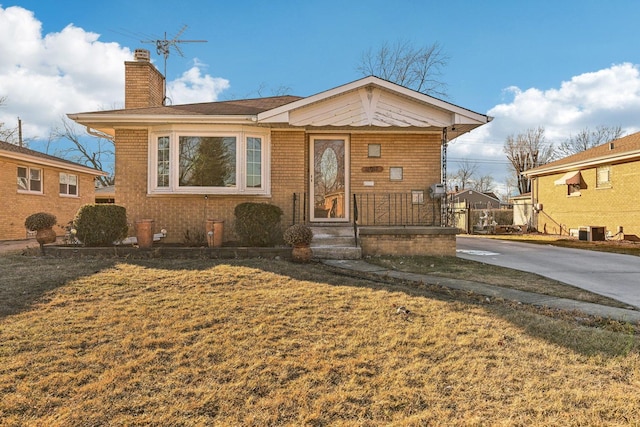 bungalow with a front lawn and central air condition unit