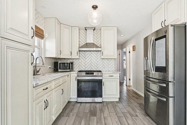 kitchen featuring decorative light fixtures, sink, decorative backsplash, stainless steel appliances, and wall chimney range hood