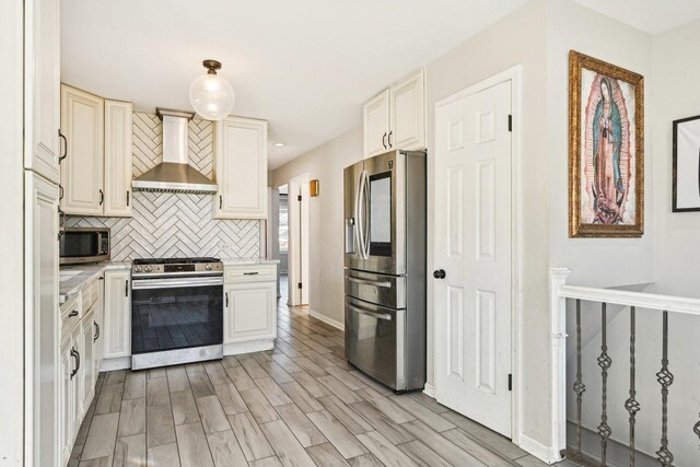 kitchen with pendant lighting, sink, stainless steel appliances, light stone countertops, and wall chimney exhaust hood