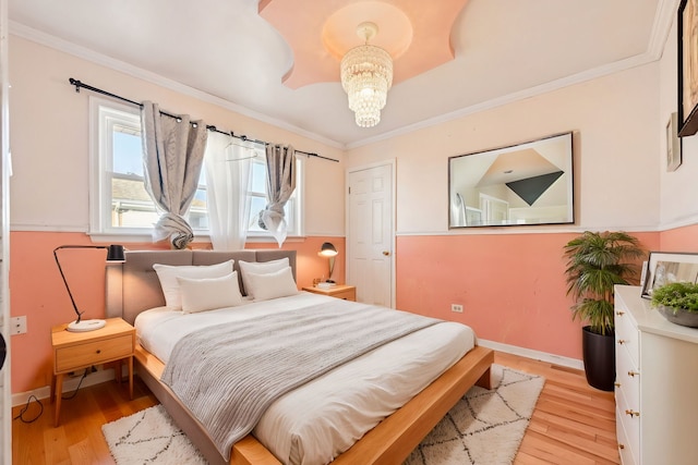 bedroom with an inviting chandelier, crown molding, and light hardwood / wood-style flooring