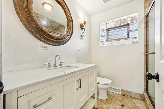 bathroom featuring tile patterned floors, vanity, toilet, and a shower with shower door