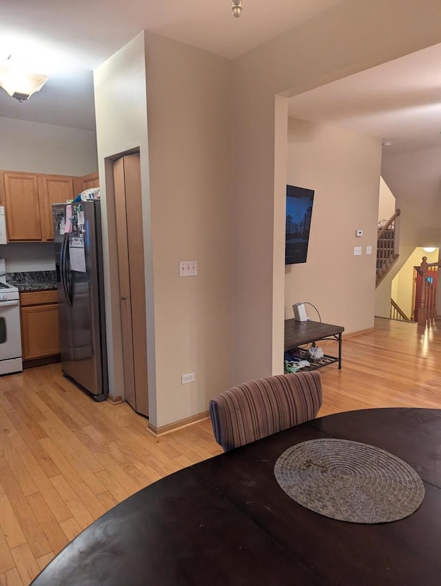 kitchen featuring white gas range, stainless steel fridge with ice dispenser, and light wood-type flooring