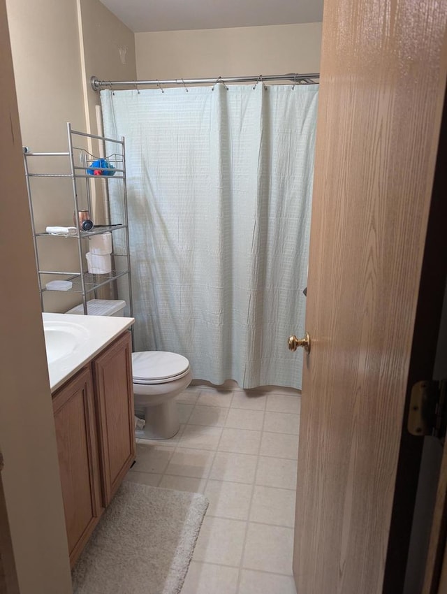 bathroom with toilet, vanity, and tile patterned floors