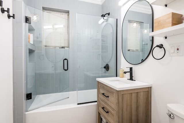 full bathroom featuring vanity, combined bath / shower with glass door, ornamental molding, and toilet