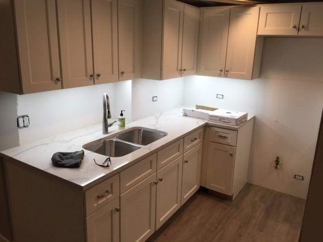 kitchen featuring light stone countertops, dark hardwood / wood-style floors, and sink