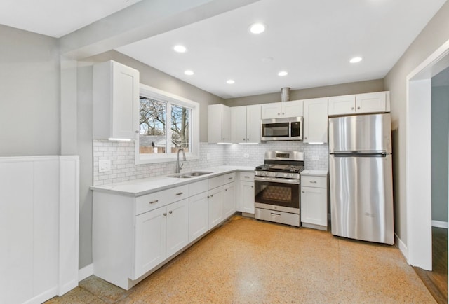 kitchen featuring backsplash, sink, stainless steel appliances, and white cabinetry