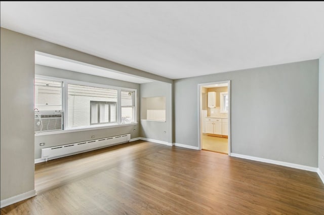 interior space with cooling unit, connected bathroom, wood-type flooring, and a baseboard radiator