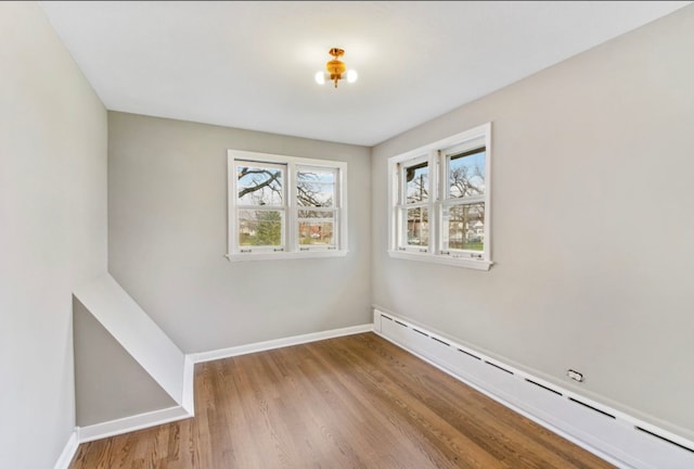 unfurnished room with light hardwood / wood-style floors and a baseboard radiator