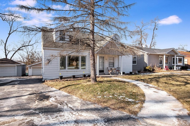 view of front of home with a garage, an outdoor structure, a front yard, and covered porch