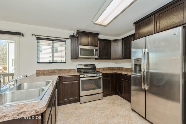 kitchen featuring dark brown cabinetry, sink, kitchen peninsula, and appliances with stainless steel finishes