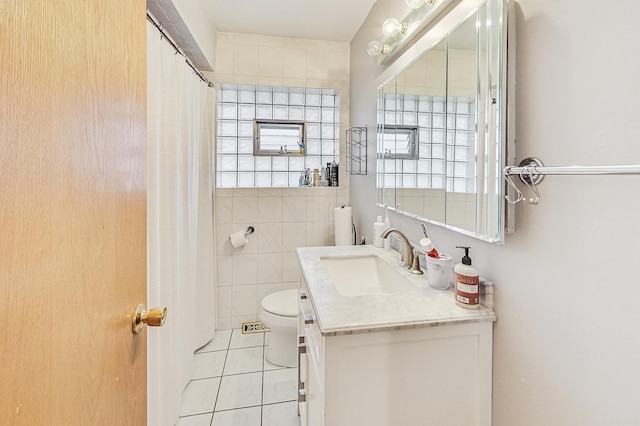 bathroom featuring toilet, vanity, tile patterned flooring, tile walls, and walk in shower