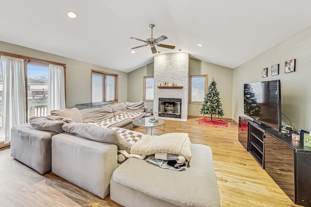 living room featuring a brick fireplace, hardwood / wood-style flooring, lofted ceiling, and ceiling fan